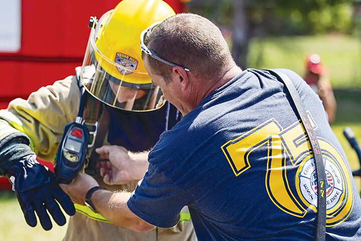 Cedar Hill Fire Capt. Jason Barton helps Evan Brakefield, 13, of Potosi try on protective equipment worn by firefighters.